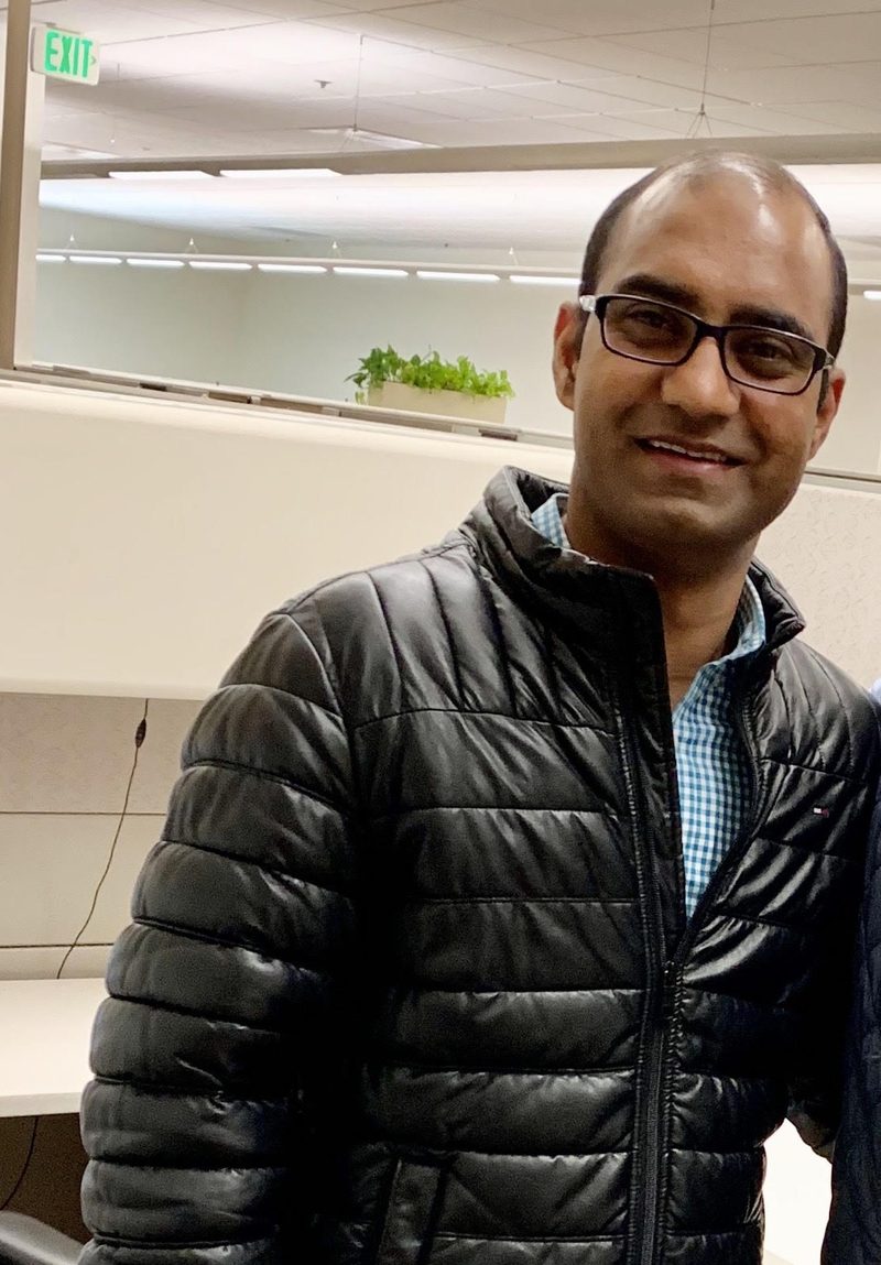 Portrait of Devendra Singh, smiling, wearing glasses